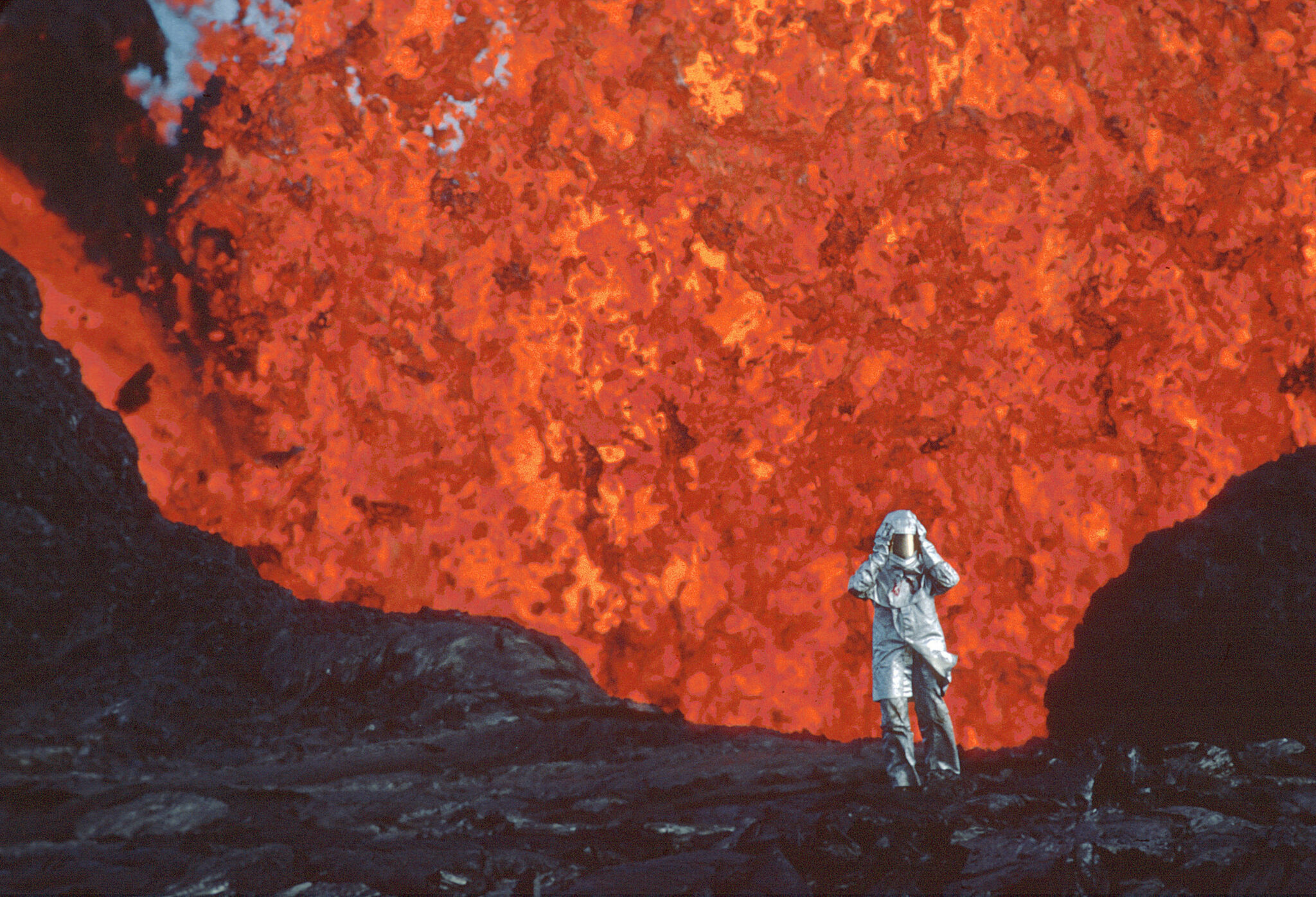 Katia Krafft, vêtue d'une combinaison aluminisée, se tient près d'une éruption de lave au volcan Krafla, en Islande. © Image'Est